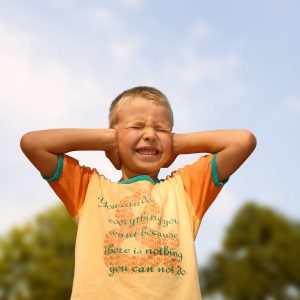 A young boy covering the ears by hands